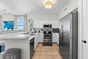 A modern kitchen with white cabinetry, stainless steel appliances, and a large island. - 3b3ba | Gulf Front | Pool, Hot Tub | Beach Chairs! (Panama City Beach)