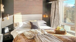 A neatly made bed with a blanket, pillows, and a bedside table with a lamp. - 1 bedroom accommodation in Sandgreen (Sandgreen)