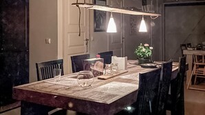 Un espace de restauration en plein air avec une table en bois, des chaises, des lampes suspendues et une plante en pot.