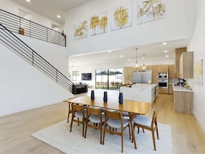 Una cocina amplia con electrodomésticos modernos, un comedor con una gran mesa de madera y una escalera que conduce a un nivel superior.