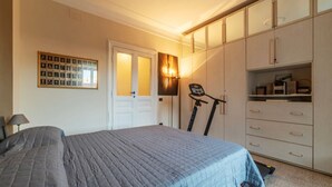 Una camera da letto con un letto, un tapis roulant, un armadio e una cornice appesa al muro.