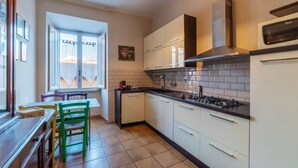 Una cucina con mobili bianchi, un piano di lavoro nero, un fornello e un forno a microonde.