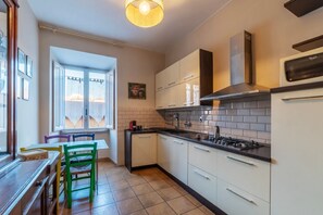 A kitchen with white cabinets, a black countertop, a stove, and a microwave.