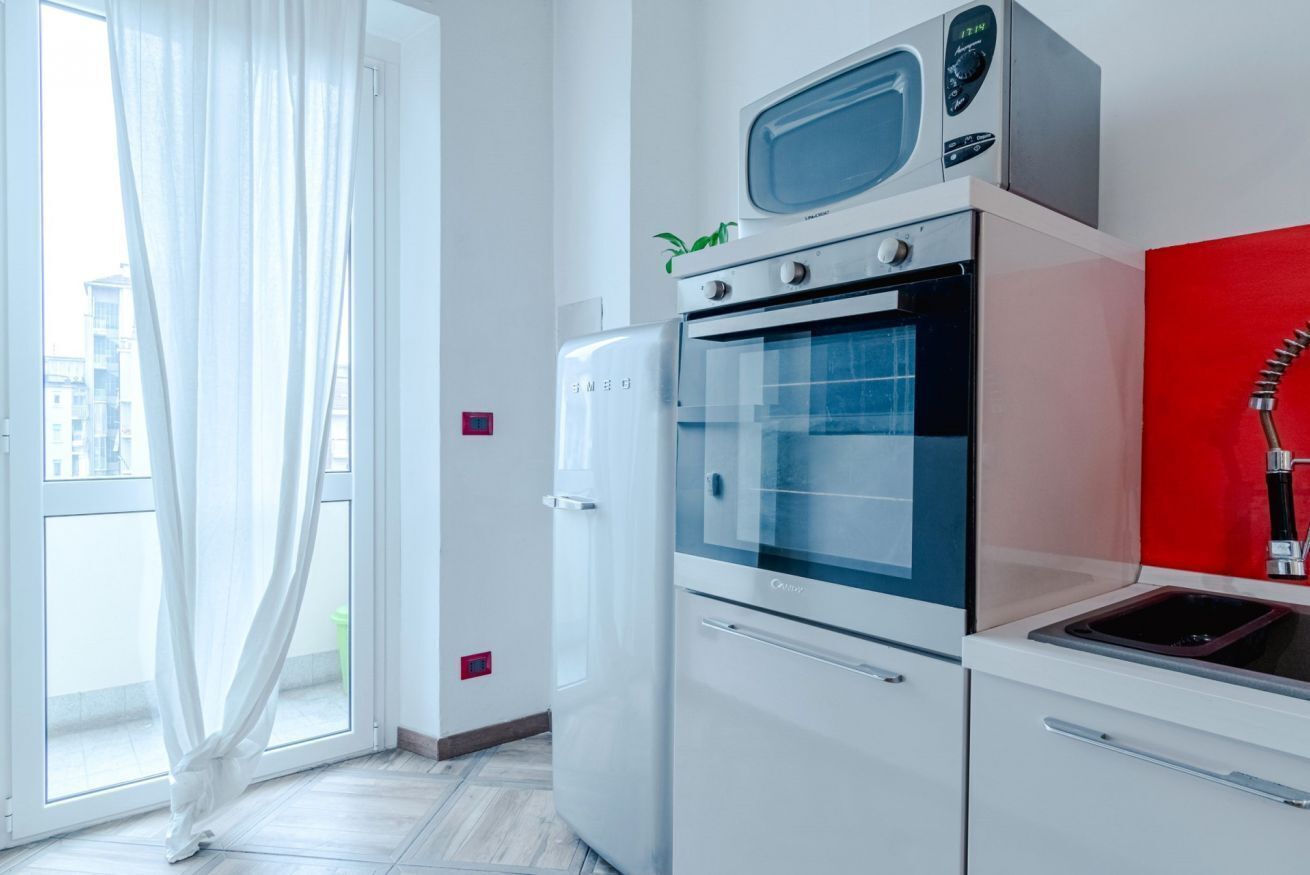 A kitchen with a microwave, oven, and sink.