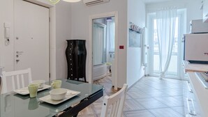 Una cucina moderna con zona pranzo, mobili bianchi e un'ampia finestra.