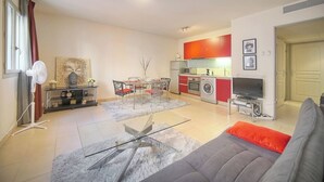 Een modern appartement met een eethoek, keuken, woonkamer en een groot raam.