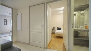 Een hotelkamer met een bed, nachtkastje, spiegel en douche.