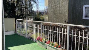 Un balcon agrémenté d’un revêtement de sol synthétique vert, de rampes blanches et de jardinières.