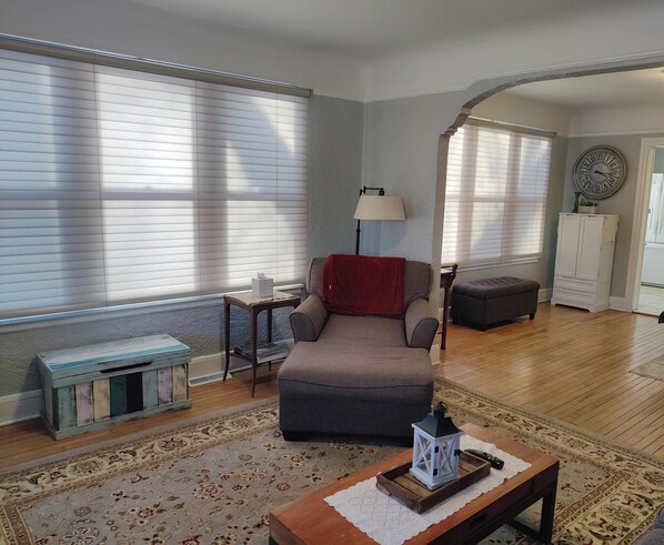 A living room with a grey sofa, a small table with a lantern, a lamp, and a cabinet.