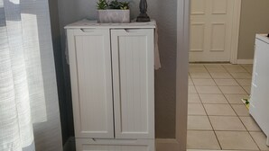 Une pièce avec un plancher en bois, une armoire blanche, une horloge murale et une porte qui donne sur une autre pièce.