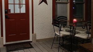 Une terrasse en bois avec une porte rouge, une décoration en forme d’étoile et une table entourée de chaises.