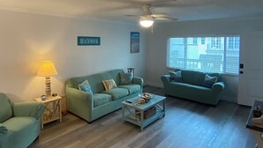 A living room with two light blue sofas, a coffee table, a lamp, and a ceiling fan.