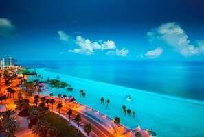 A coastal resort with a beachfront, palm trees, and a road leading to the beach.