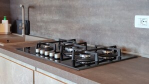 Une cuisine équipée d’une cuisinière à gaz, d’un évier et d’un plan de travail.