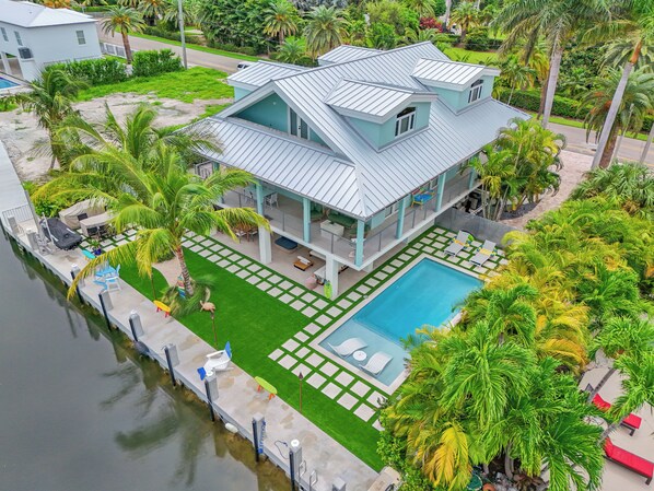 A two-story house with a swimming pool, surrounded by palm trees and a dock. - Luxurious 3-bedroom home with Pool and Dock in Key Colony Beach (Key Colony Beach)