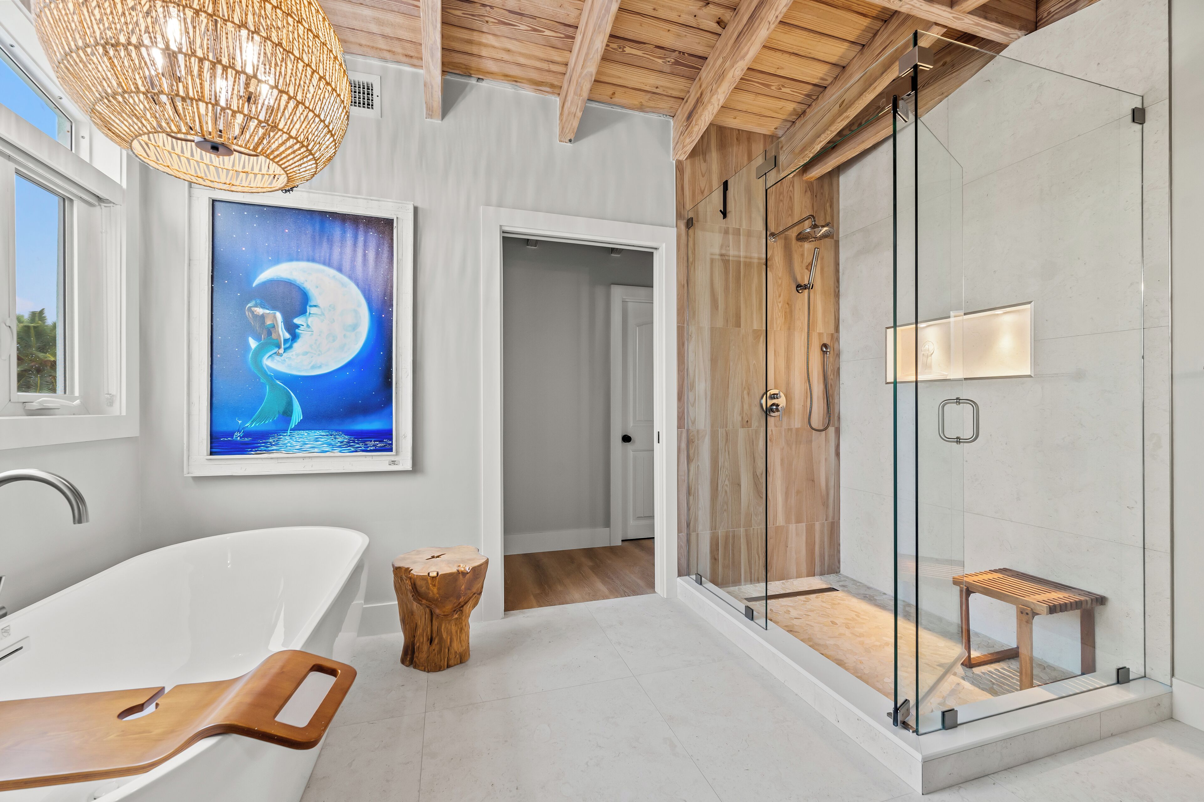 A modern bathroom with a freestanding bathtub, a glass-enclosed shower, and a wooden bench.