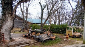 A rustic outdoor area with a wooden bench, a small table, and a fire hydrant. - Unique Train Caboose Tiny House & event space. Antique shops & Norman close by  (Lexington)