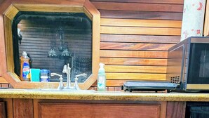 A compact kitchen area with a wooden countertop, a sink, and a microwave. - Unique Train Caboose Tiny House & event space. Antique shops & Norman close by  (Lexington)