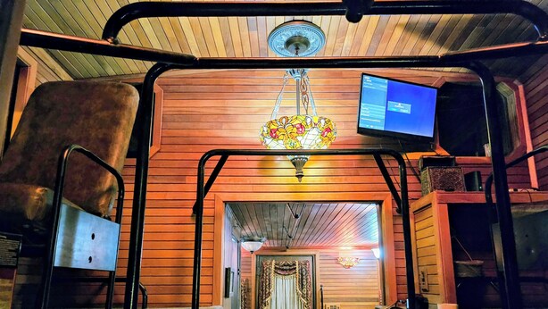 A cozy room with a wooden interior, a bed with a blanket, a desk with a computer, and a chandelier. - Unique Train Caboose Tiny House & event space. Antique shops & Norman close by  (Lexington)
