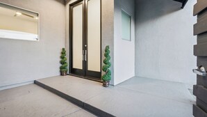 A modern entrance with a glass door, a small potted plant, and a light-colored wall. - The Hollywood Hills Luxury Nest with Views, Pool and Spa. (Los Angeles)