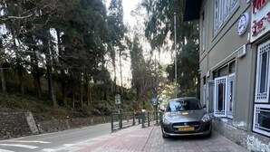 En bil parkeret på en brobelagt fortov ved siden af en bygning med traditionelle vinduer.