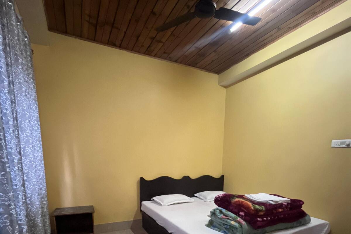 Ein Schlafzimmer mit einem Bett, einem Nachttisch, einem Deckenventilator und einer grünen Willkommensmatte.