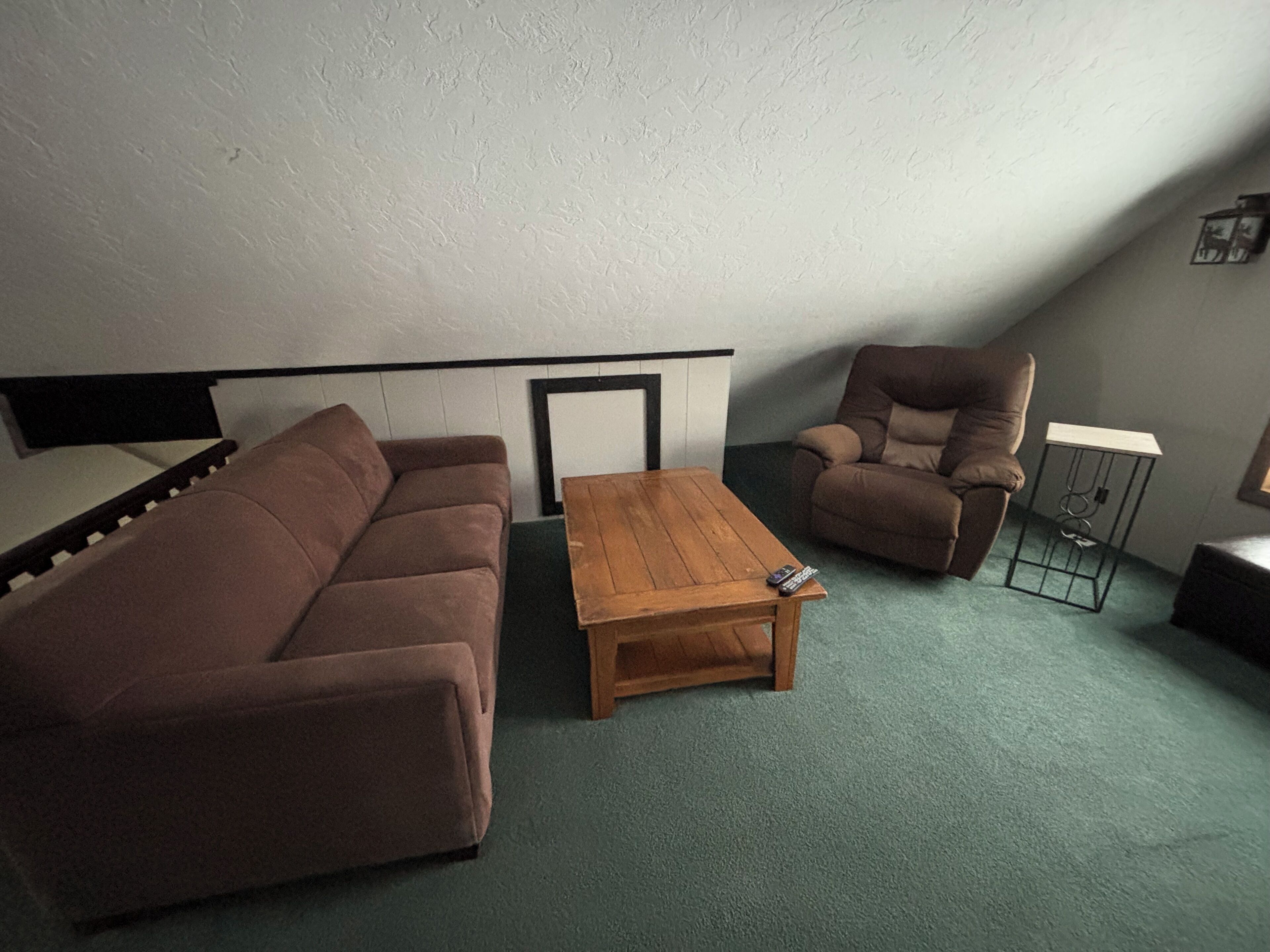A living room with a brown sofa, a wooden coffee table, and a recliner.