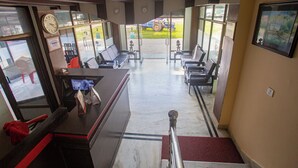 A reception area with a desk, chairs, a clock, and a view of the outside.
