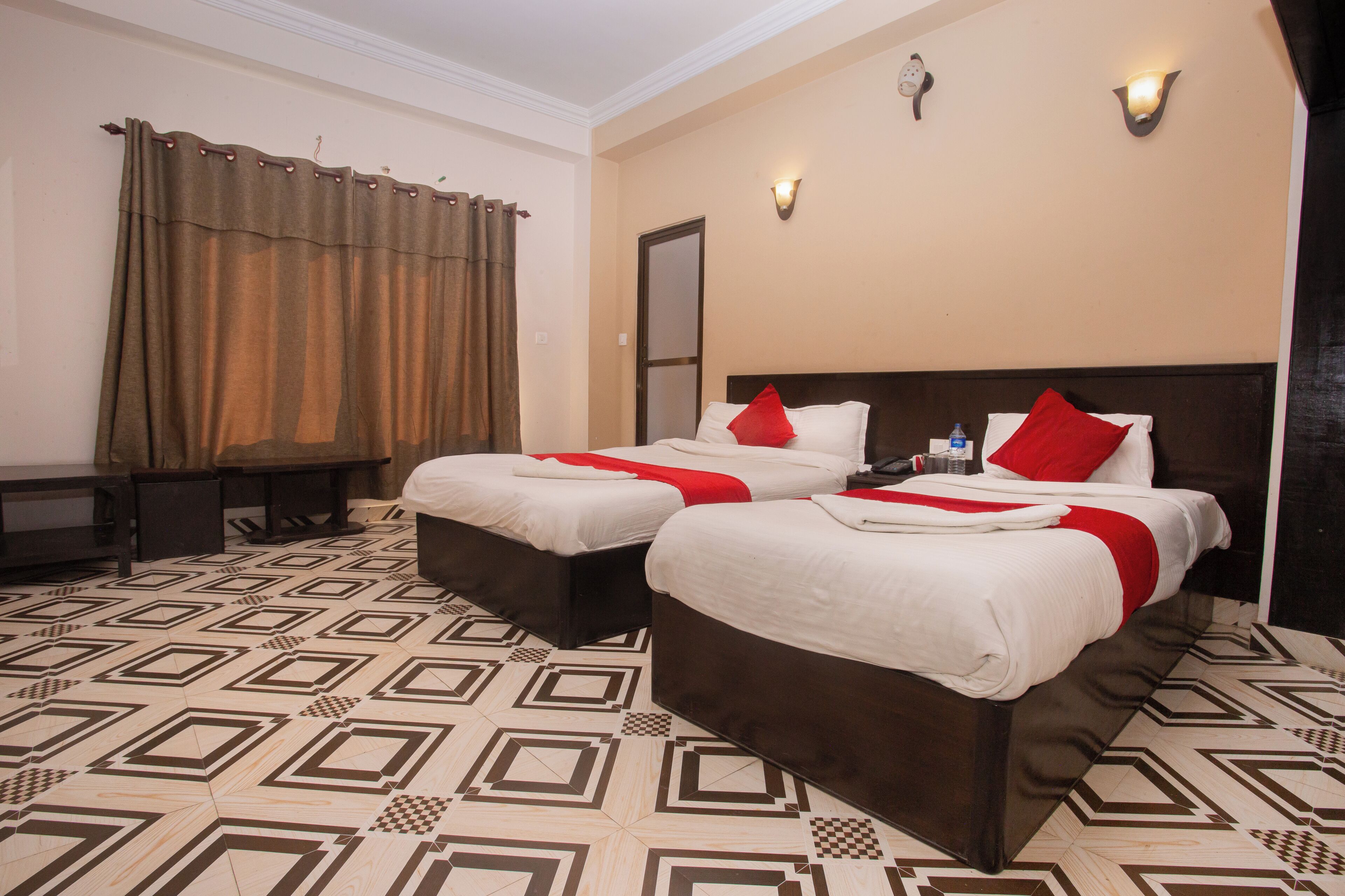 A hotel room with two beds, a desk, and a patterned floor.