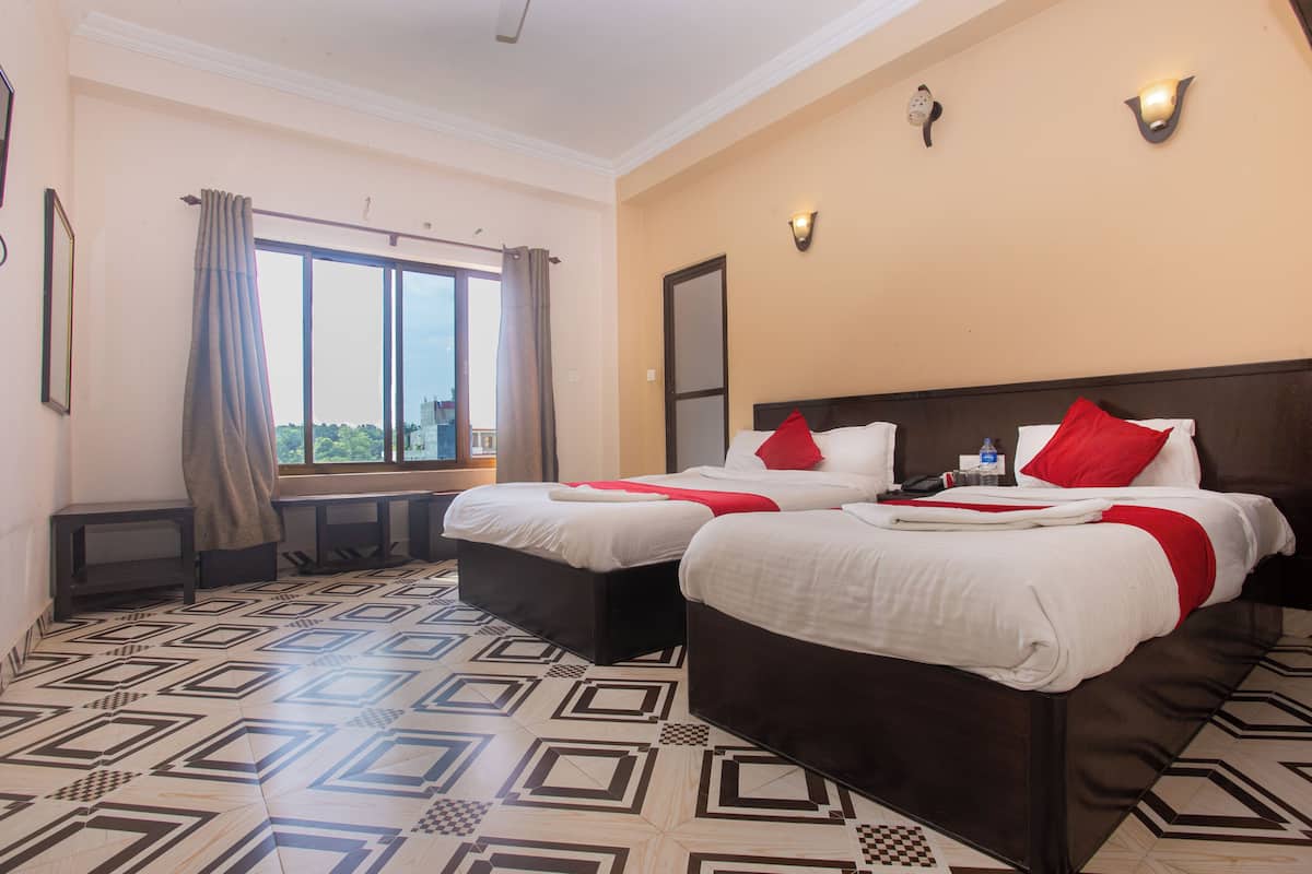 A hotel room with two beds, a large window, and a patterned floor.