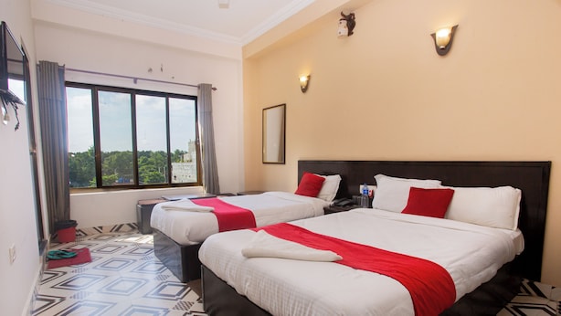 A hotel room with two beds, a large window, and a patterned floor.