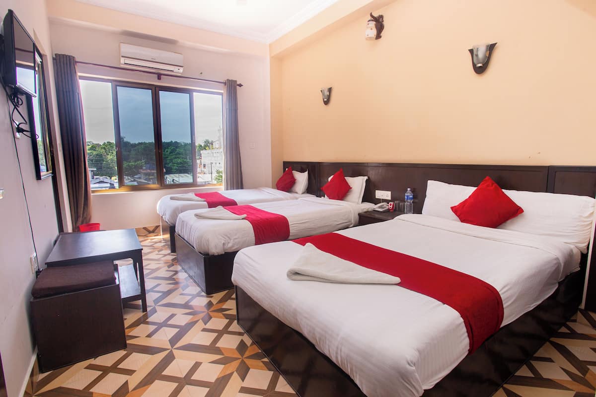 A hotel room with two beds, a small table, and a window with curtains.