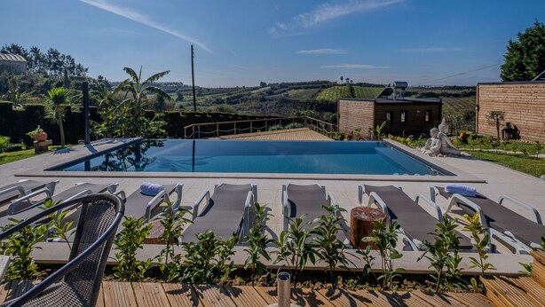 A swimming pool with lounge chairs and a view of hills. - Villas P Moinho - 04 Macieira (Obidos)