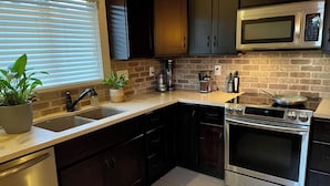 A modern kitchen with a brick backsplash, stainless steel appliances, and dark cabinetry.