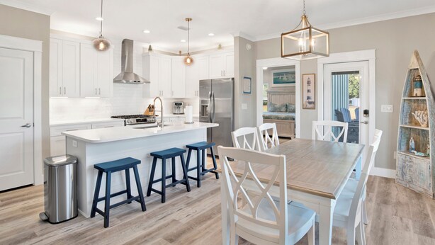 A modern kitchen with white cabinetry, a central island with stools, stainless steel appliances, and pendant lighting. - Touchdown Hideaway! Beach/OWA/Sports/Shopping (Foley)