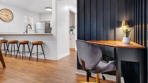 Une cuisine moderne dotée d’un plan de travail en bois, de tabourets de bar et d’un coin repas avec une table et des chaises.