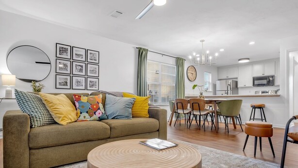 Un salon moderne avec un canapé, une table basse ronde et un coin repas comprenant des chaises et une table.