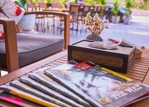 Una mesa de madera con revistas, una cesta de mimbre y un jarrón con flores secas.