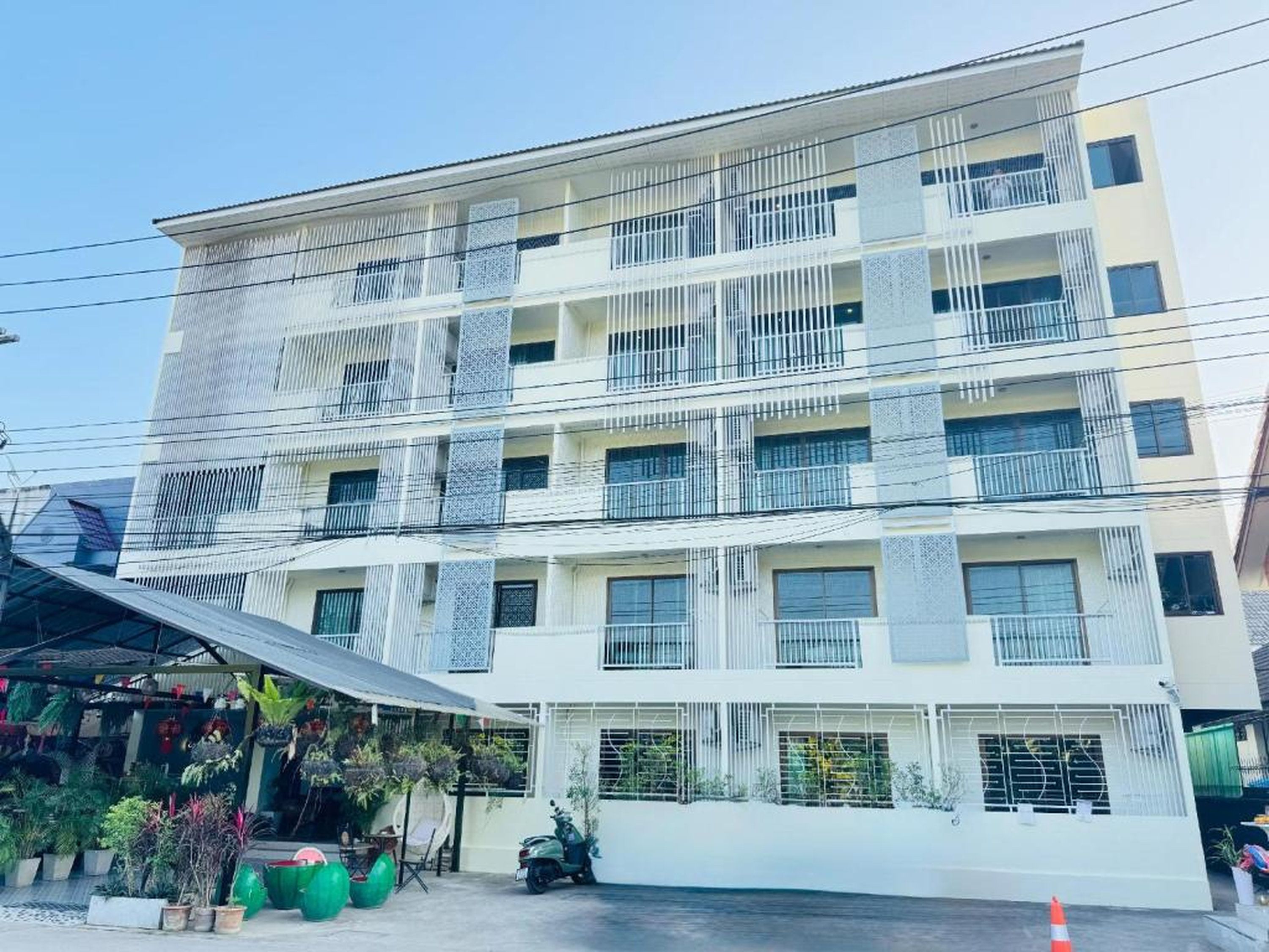 A multi-story building with balconies, a covered entrance, and a small parking area.
