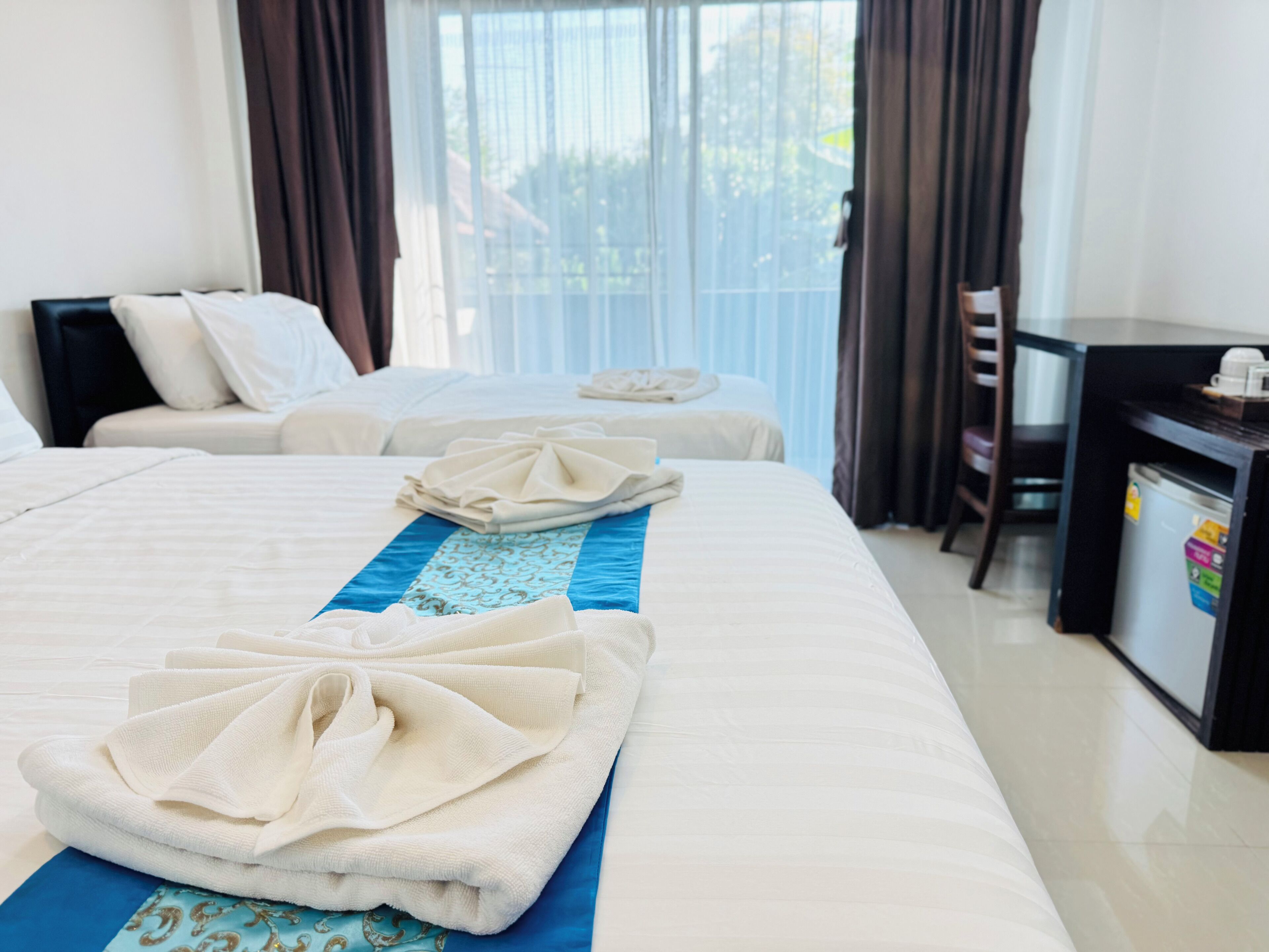 A hotel room with two beds, a desk, and a minibar.