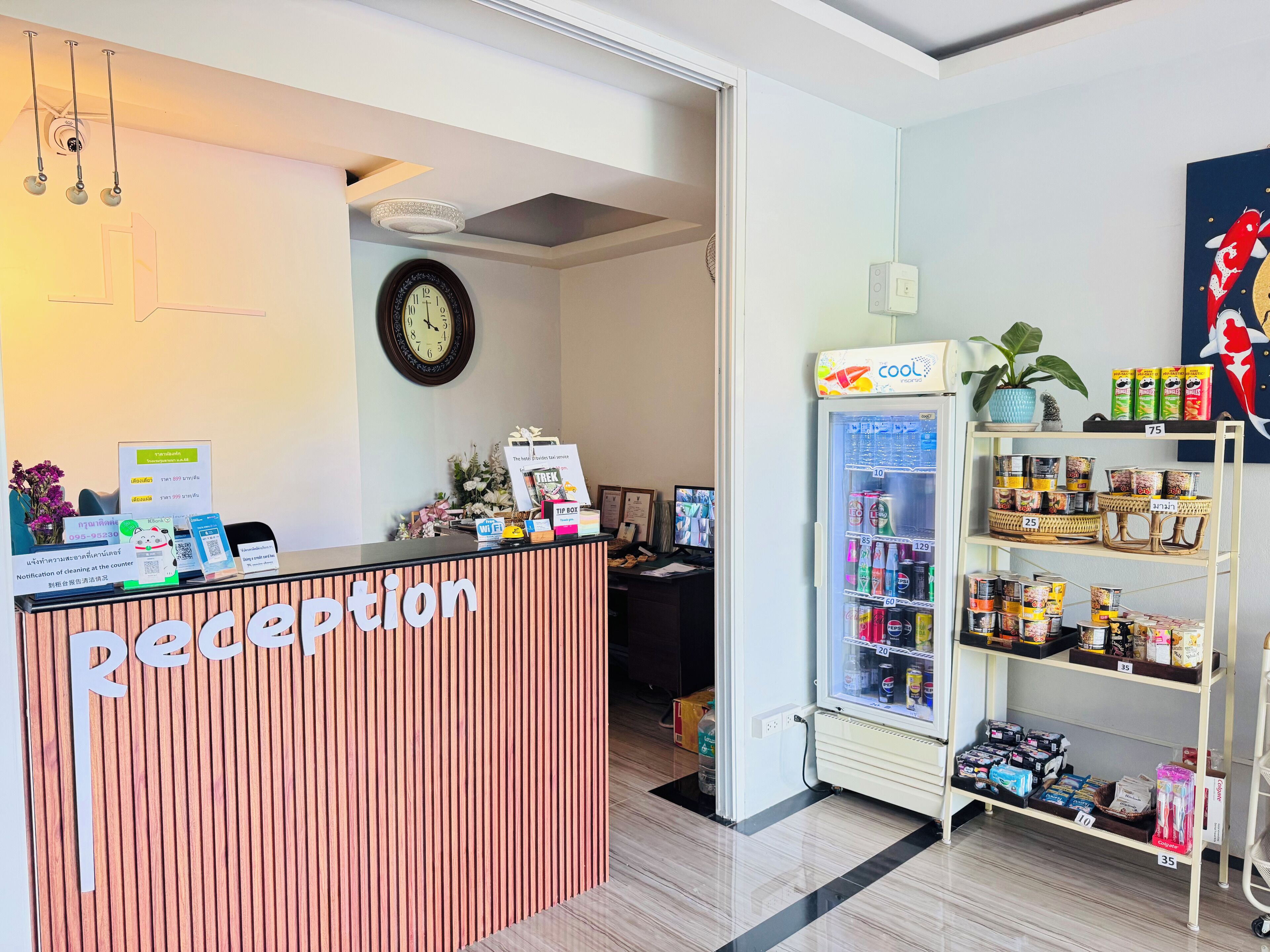 Un espace d’accueil comprenant un comptoir de réception en bois, une horloge, un distributeur automatique et une étagère avec des en-cas.