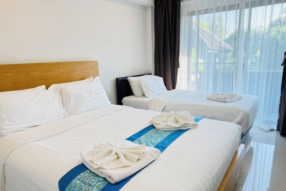 Una habitación de hotel con dos camas, cada una con ropa blanca y un detalle decorativo azul.