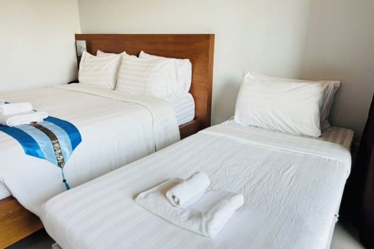A hotel room with two beds, each with white linens and pillows.