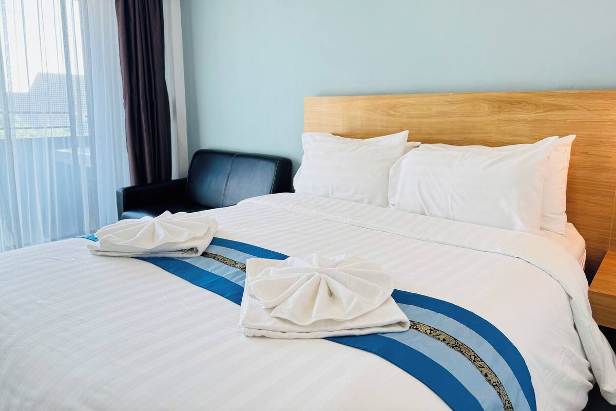 Una habitación de hotel con una cama bien hecha, un cabecero de madera y una silla.