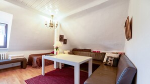 A living room with a white table, brown sofa, red rug, and a chandelier.