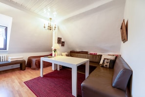 A living room with a white table, brown sofa, red rug, and a chandelier.