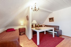 Un dormitorio con cama, mesita de noche, mesa, lámpara, sofá y candelabro.