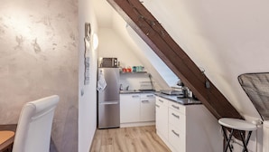 A compact kitchen with white cabinets, a stainless steel refrigerator, and a small countertop.