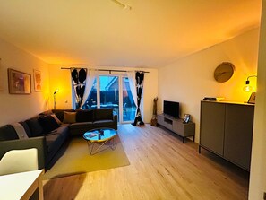 Una sala de estar con un sofá, una mesa de centro, televisor y un mueble.