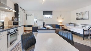 A modern kitchen with a microwave, oven, and dining area. - Apartment Knodel No. 3 in Kraichgau – Quiet, Wi-Fi & Ideal for Business (Sachsenheim)